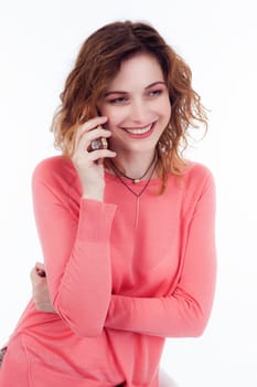 Portrait of cute joyful woman with trendy hairstyle wearing basic t-shirt talking on mobile phone isolated over white background.