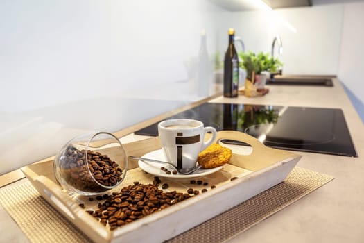 A tray of coffee with spilled coffee beans on a table. In the background is a blurred modern kitchen.