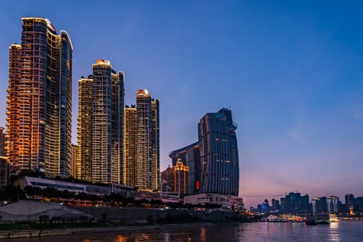 Chongqing, China -  August 2019 : Night view of the modern commercial and business buildings on the riverside at dusk