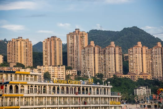 Chongqing, China - August 2019 : Luxury passenger ship and the panorama of Chongqing town on the Yangtze river, the starting point for small boat trip cruises along this mighty river