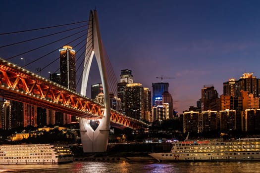 Chongqing, China -  August 2019 : Illuminated DongShuiMen road bridge over and across mighty Yangtze river in Chongqing town at dusk
