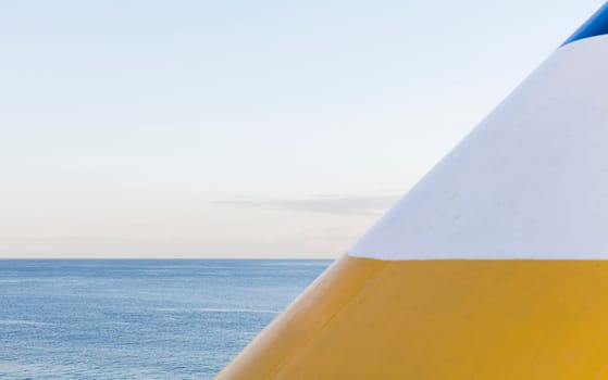 Geometry of a chimney of a cruise ship and the horizon of the sea, in yellow, blue and white