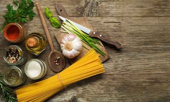 Pasta with spices and ingredients on old wooden table