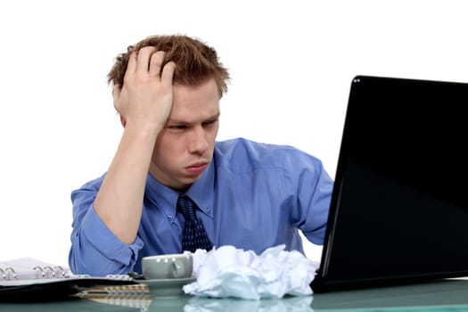 young businessman working on laptop looking exasperated