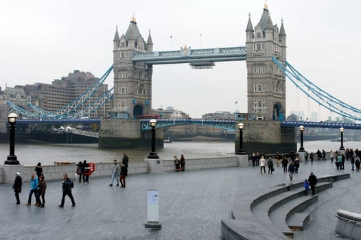 London,United Kingdom – November 28,2014: The side view of Tower Bridge with a waterfront promenade of the Southwark borough as people walk along in London on November 28.