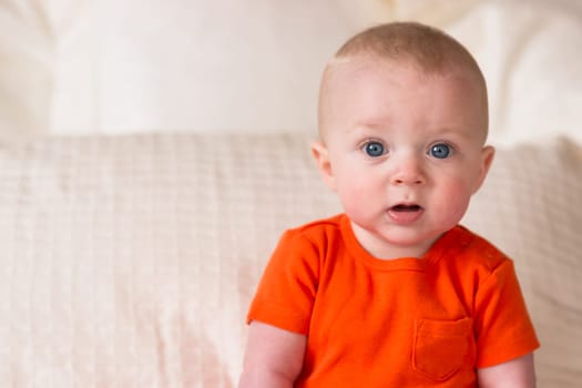A young boy sits up in bed looking surprised