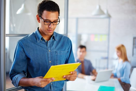 Young businessman reading paper in working environment