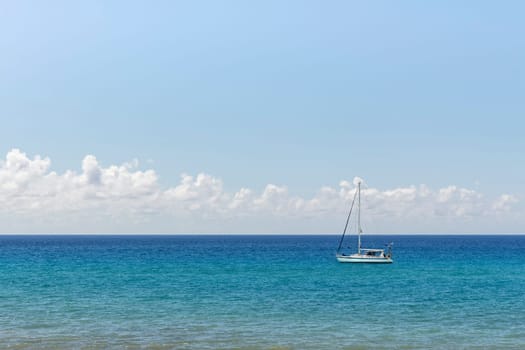 Minimalist seascape with a white boat on a turquoise waters and cloudy sky