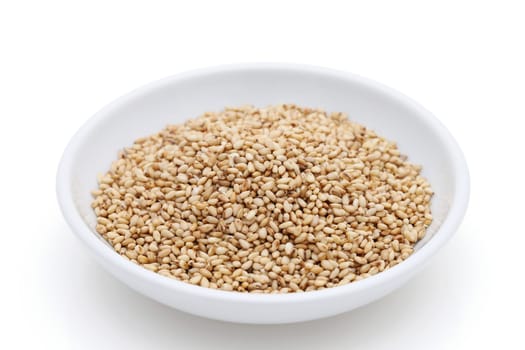 White sesame seeds in a dish on white background