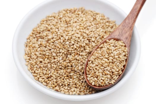 White sesame seeds with wooden spoon in a dish on white background