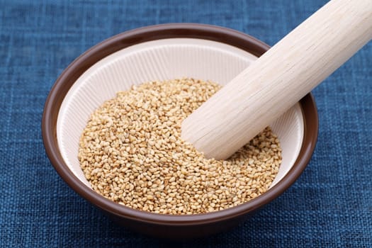 White sesame seeds with wooden pestle in a mortar on table