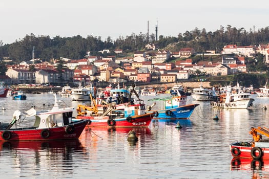 Arosa Island, Spain - 01, 22, 2016: Colored fishing boats moored in the port with the village in the background