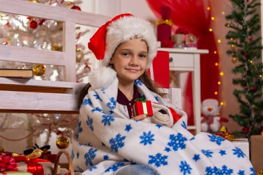 Girl dressed in A New Year's Cap sits covered in plaid