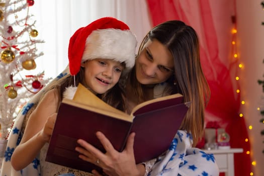 Girl with child reading a book in a decorated christmas room
