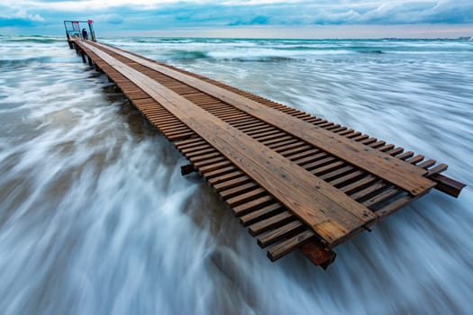 Wooden pier in a storm covered with a wave, long exposure