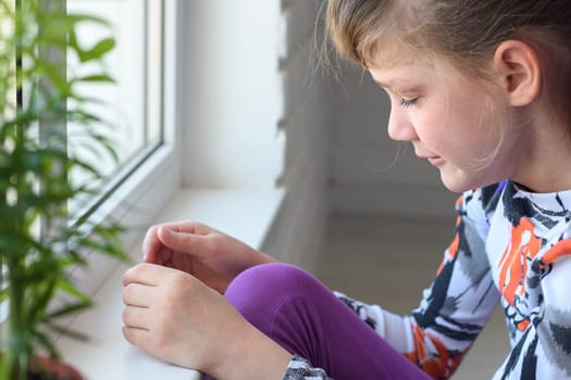 Offended girl cries at the window in the room