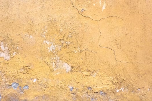 Grunge plaster wall with yellow scratched background. Old wall with peel swamp color stucco texture. Vintage wallpaper. Decay and cracks. Rough abstract surface.