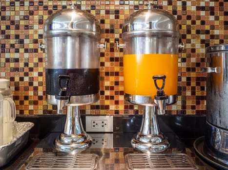 Fruit juice dispensers and coffee & tea water on a self service breakfast counter in a hotel.