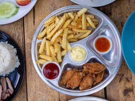 The fried chicken drumstick and french fries on wooden background.