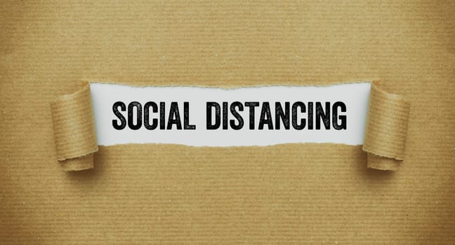 Torn paper revealing the words Social distancing