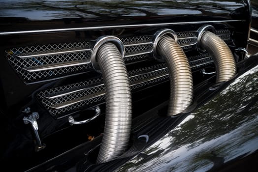 three chrome exhaust pipes on a black oldtimer car
