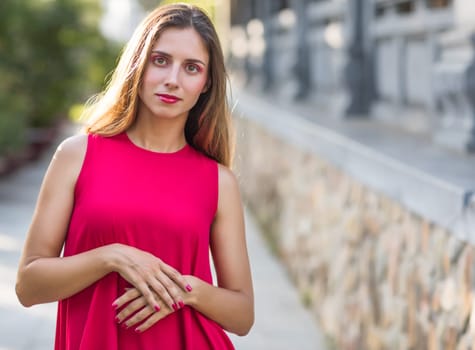 Fashion portrait of a beautiful woman in red dress outdoor