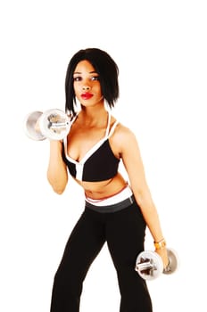 A young pretty woman standing in the studio, working out with two.dumbbells in her black sports outfit, isolated for white background.