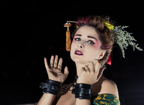 Woman in Japanese Geisha kimono in handcuffs and choker
