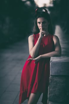 Fashion portrait of a beautiful woman in red dress and horns. Halloween