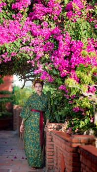 Fine art portrait of beautiful woman in Japanese Geisha style wearing kimono in a garden