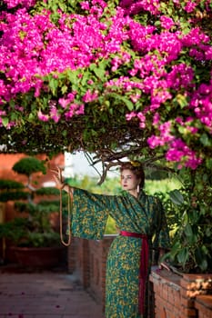 Fine art portrait of beautiful woman in Japanese Geisha style wearing kimono in a garden