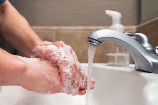 Washing hands with soap and water in bathroom sink, protection against viruses and bacteria, hygiene to stay healthy