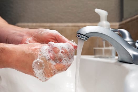 Washing hands with soap and water in bathroom sink, protection against viruses and bacteria, hygiene to stay healthy