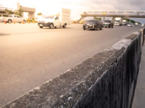 Highway traffic in sunset. Road with metal safety barrier or rail.