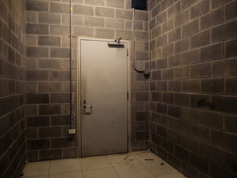 The metal Beige back door of building with old brick wall