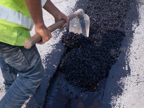 Worker use vibratory plate compactor compacting asphalt at road repair