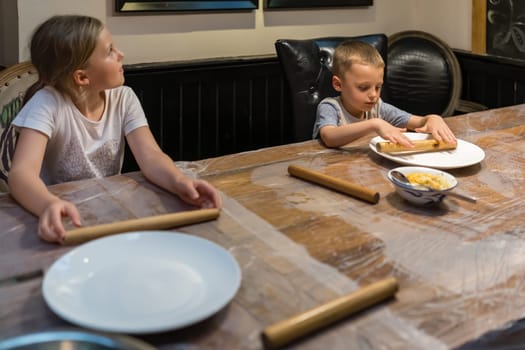 Picture of kids playing with wooden stick on the table while waiting for dumpling making class session to start