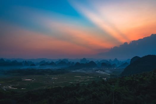 Breathtaking view of a sunset seen from the Putao Rural Scenery viewpoint in Yangshuo, China, captured on a foggy day