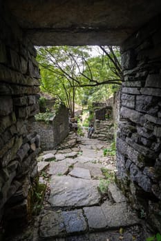 A vertical shot of people in a beautiful ancient landscape build with stones in a forest