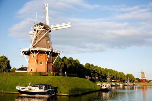 Dokkum, Friesland, The Netherlands - Jun 30, 2019  Boats on canal and windmill on fortifications of historic town Dokkum, Friesland, The Netherlands..