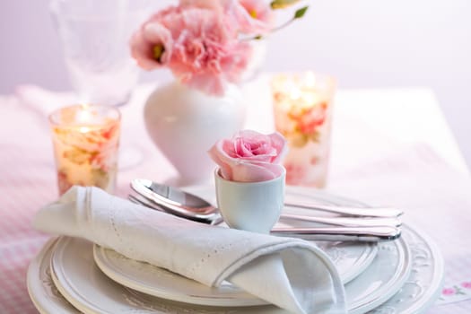 Place setting with beautiful bouquet in vase in pink and white on the kitchen table