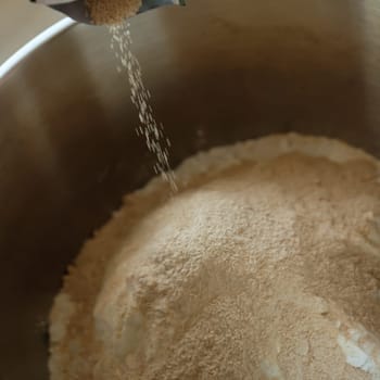 Yeast and flour in a stainless steel bowl