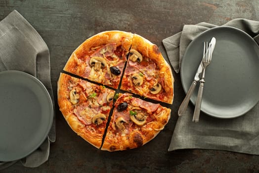 Pizza served with mozzarella cheese, ham, mushrooms, tomato sauce and fresh basil