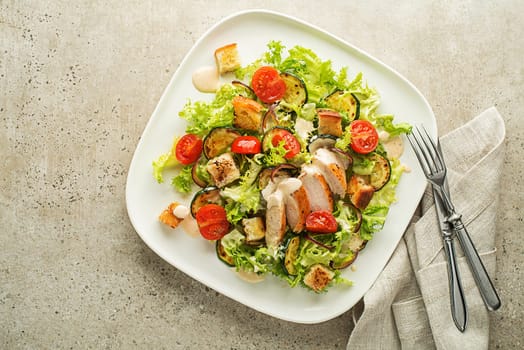 Healthy chicken meal with grilled chicken, vegetables, croutons and sauce on grey background. Healthy lunch plate.