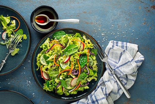Green lettuce salad meal with fresh mixed vegetables on blue table background