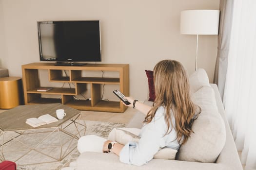 A woman on a sofa getting ready to watch TV