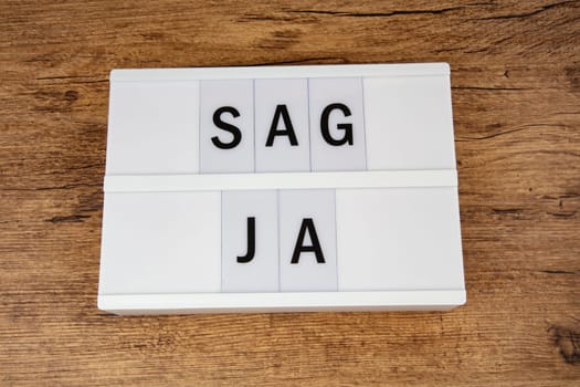 SAG JA means Say Yes on a light box on wooden Background