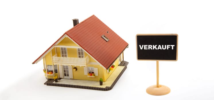 Concept Real Estate: Verkauft means Sold Business Real Estate with Toy House and little Blackboard Sign on white Background