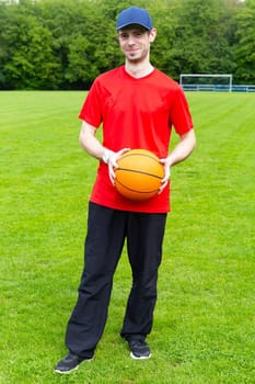 Young friendly man with basketball in outdoor sports area