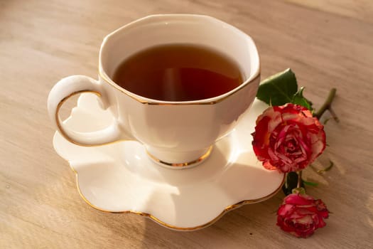 Healthy tea in white classic cup with roses, vintage